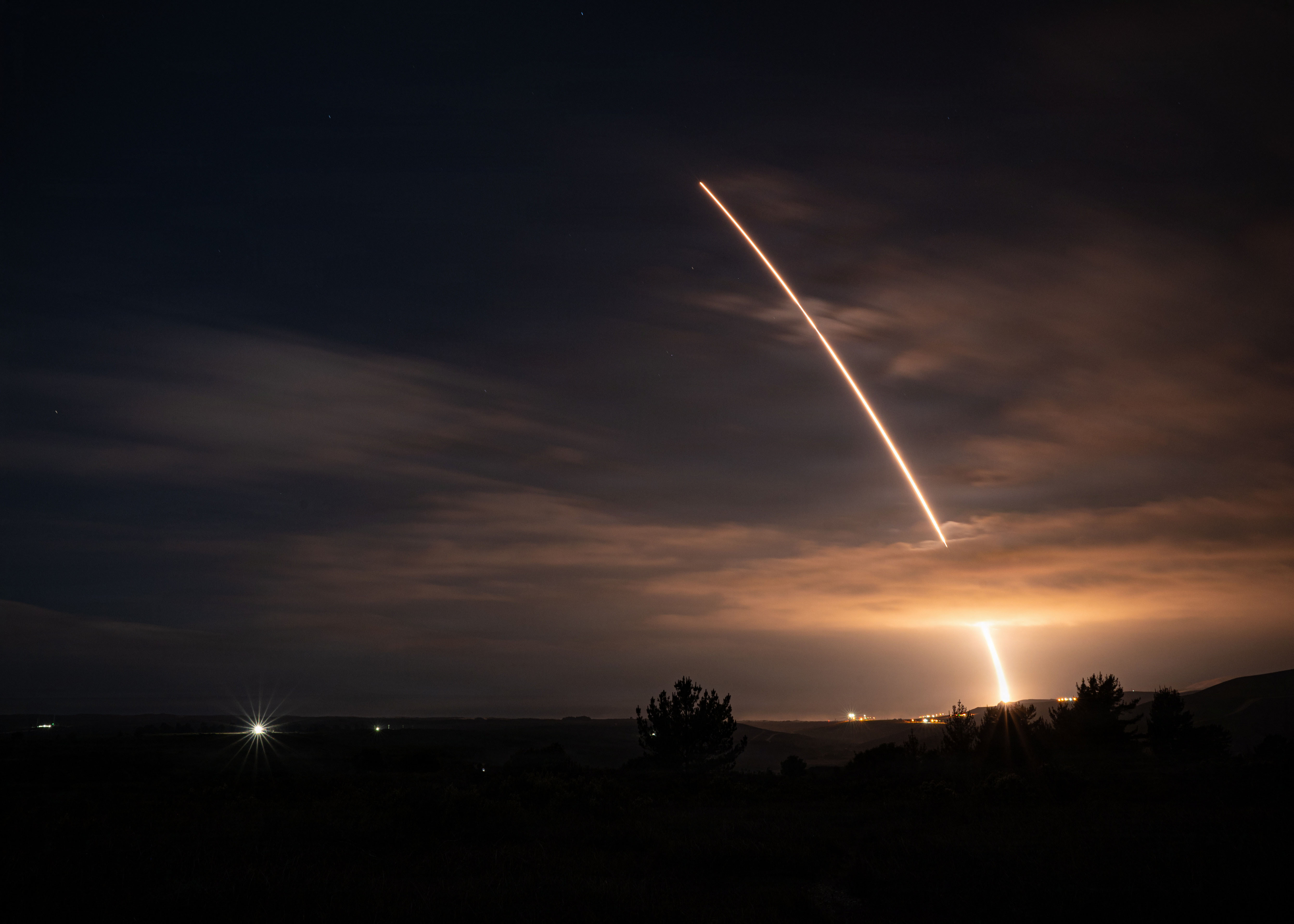An arc of light from a missile test against a dark sky